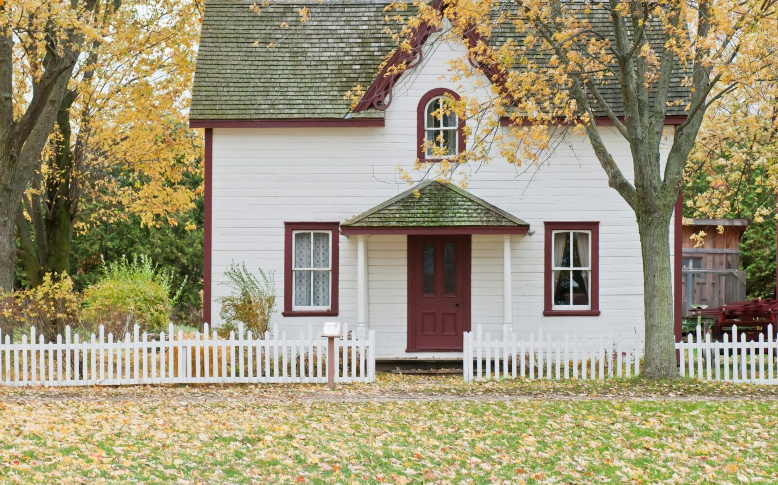 Picturesque traditional house with autumn foliage and a white picket fence in London, Ontario.